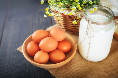 Fresh chicken eggs and a jar with milk on the kitchen table. Still life with farm products.の写真素材