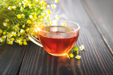 Cup of chamomile tea and a bunch of chamomile flowers on the table. Beautiful still life with herbal tea.の写真素材