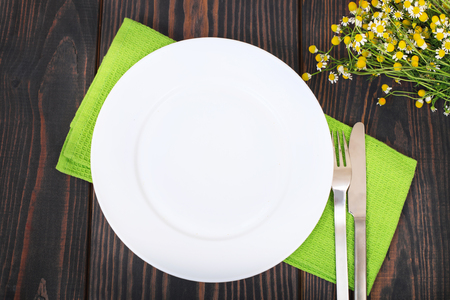 The knife, fork and white plate on a green napkin on a wooden background.の写真素材