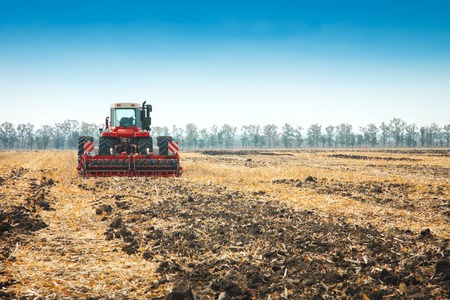 Modern tractor in the field with complex for the plowing. The concept of work in a fields and agriculture industry.の写真素材