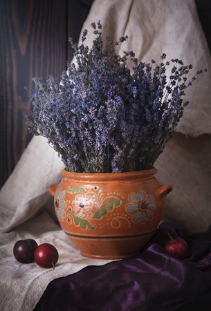 Still life with lavender in a clay jug and plums on the table. Country style.の写真素材
