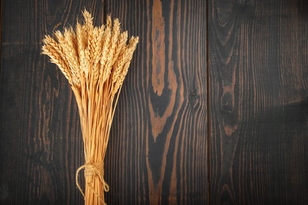 Spikes of ripe golden wheat on a wooden background. The concept of agriculture and harvesting.の写真素材
