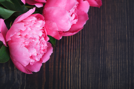 Pink peonies on a wooden table. Beautiful floral background with space for text.の写真素材