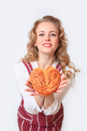 Portrait of cute smiling woman with pastries in her hands in the studio, on a gray background.の写真素材