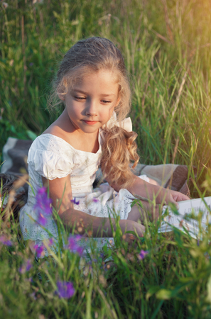 Cute little girl reading book on natureの写真素材
