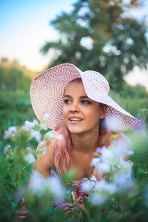 Portrait of a yong woman in a hat on nature in flowersの写真素材