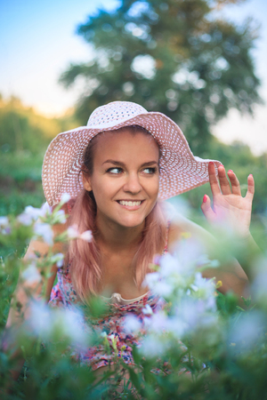 Portrait of a yong woman in a hat on nature in flowers.の写真素材