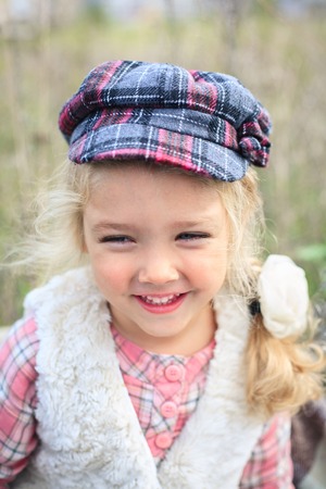 Portrait of a cute cheerful little girl on a nature in sunny autumn day.の写真素材