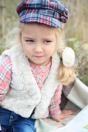 Portrait of a cute cheerful little girl on a nature in sunny autumn day.の写真素材
