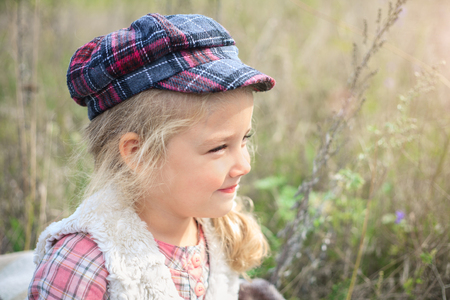 Portrait of a cute cheerful little girl on a nature in sunny autumn day.の写真素材