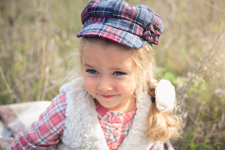 Portrait of a cute cheerful little girl on a nature in sunny autumn day.の写真素材