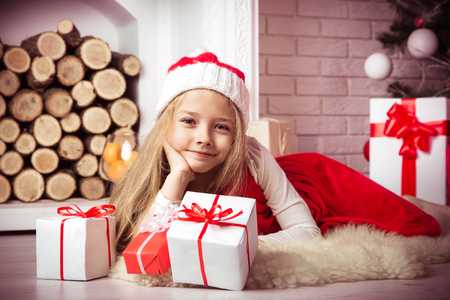 Lovely girl in santa cap lying on floor in red dress, studio shot, toning in vintage style.の写真素材