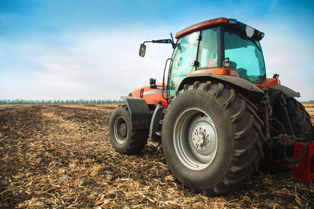 Modern red tractor in the field on a bright sunny dayの写真素材