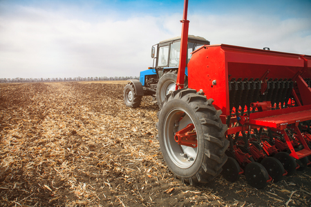 Modern tractor in the field with sowing complex. The concept of work in a fields and agriculture industry.の写真素材
