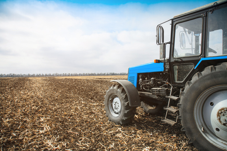 Old blue tractor in a empty field on a bright sunny day. Agricultural machinery, field work.の写真素材