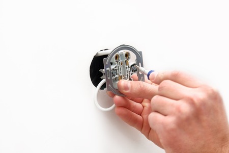 The electrician installs an electrical outlet in wallの写真素材
