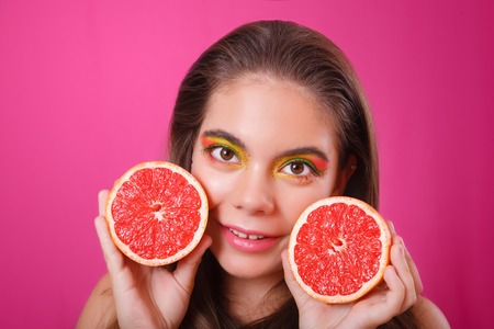 Portrait of red-haired woman with a grapefruits in hands in studio close-up .の写真素材