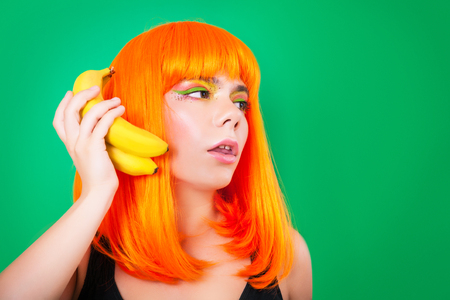 Portrait of red-haired woman with a grapefruits in hands in studio close-up .の写真素材
