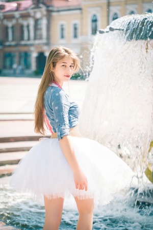 Cute young woman in fluffy skirt near the fountainの写真素材