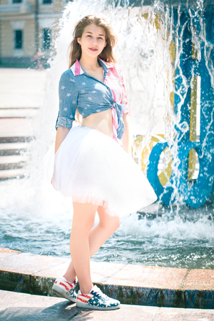 Cute young woman in fluffy skirt near the fountainの写真素材