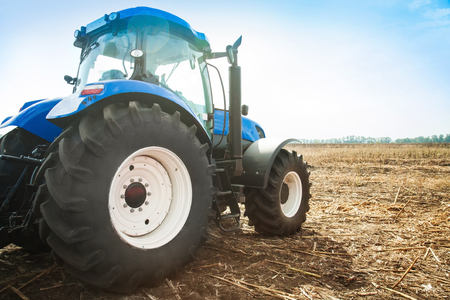 Blue tractor in a field on a bright sunny dayの写真素材