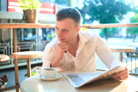 Thoughtful man reading a newspaper in a street cafe at lunch. Concept of business people.の写真素材