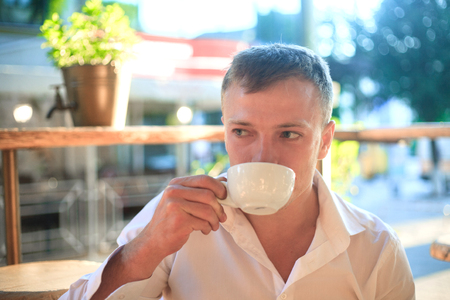 Young man enjoy on coffee break, outdoors portraitの写真素材
