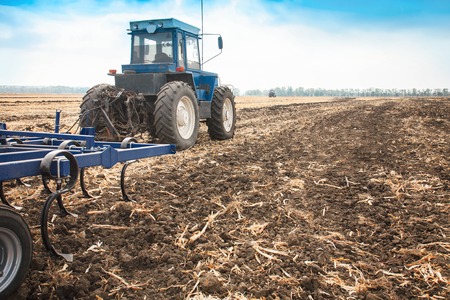 Blue tractor in a field on a sunny day. The concept of work in a fields and agriculture industry.の写真素材