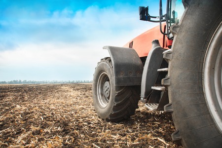 Modern red tractor in the field close-up on a bright sunny dayの写真素材