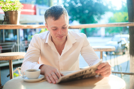 Thoughtful man reading a newspaper in a street cafe at lunch. Concept of business people.の写真素材