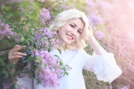 Beautiful woman in a spring garden with blooming lilacs.の写真素材