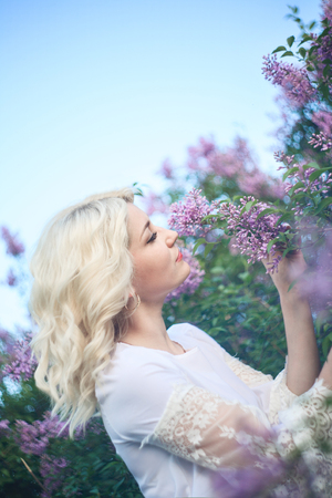 Beautiful woman in a spring garden with blooming lilacs.の写真素材