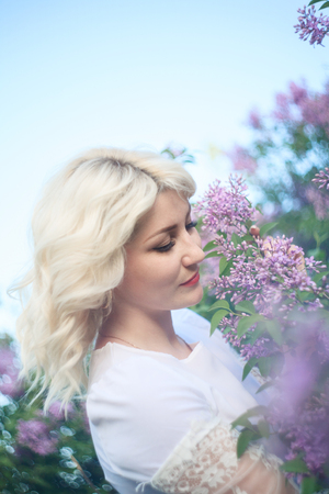Beautiful woman in a spring garden with blooming lilacs.の写真素材