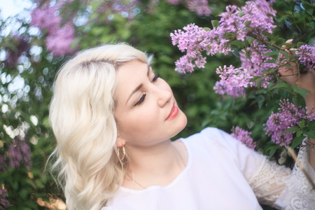 Beautiful woman in a spring garden with blooming lilacs.の写真素材