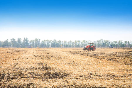 Modern red tractor in the field on a bright sunny dayの写真素材