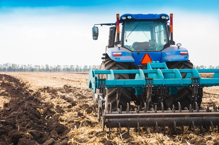A modern tractor on a plowed field on a clear day. The concept of agriculture industry.の写真素材
