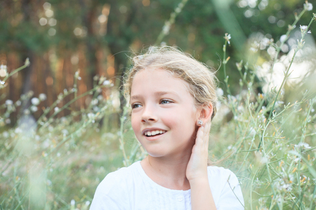 Portrait of a cute little girl on the nature in flowers while walking.の写真素材