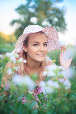 Portrait of a young woman in a hat on nature in flowers.の写真素材