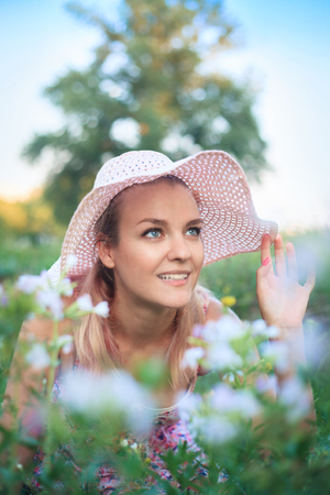 Portrait of a young woman in a hat on nature in flowers.の写真素材
