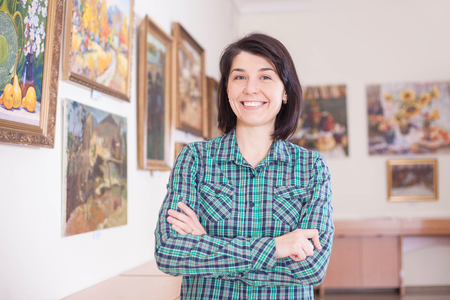 A young pretty smiling woman in a picture gallery.の写真素材