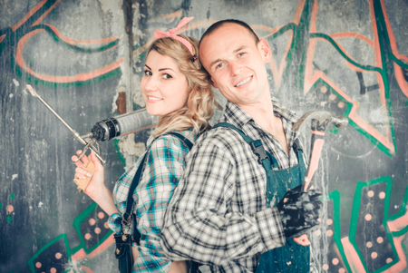 Portrait of a young man and woman in overalls with tools for the repair of the interior in hands. Concept of construction and home repair.の写真素材