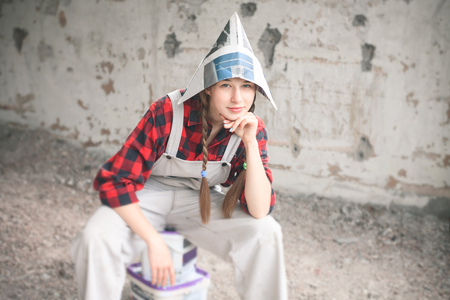 Smiling young woman in newspaper hat holding paint bucket. Repair home concept.の写真素材