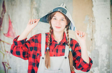 Portrait of young smiling beautiful woman in newspaper hat. Repair home concept.の写真素材