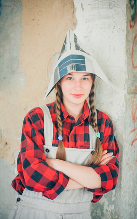 Portrait of young smiling beautiful woman in newspaper hat. Repair home concept.の写真素材