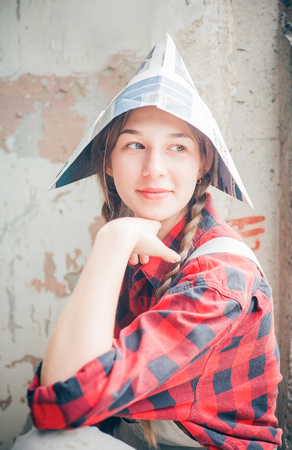 Portrait of young smiling beautiful woman in newspaper hat. Repair home concept.の写真素材
