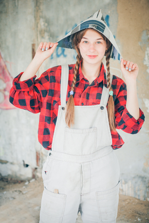 Portrait of young smiling beautiful woman in newspaper hat. Repair home concept.の写真素材