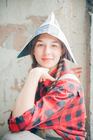 Portrait of young smiling beautiful woman in newspaper hat. Repair home concept.の写真素材