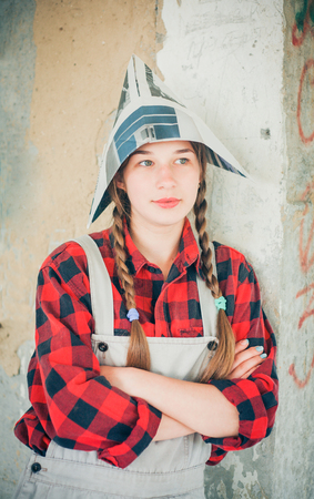 Portrait of young smiling beautiful woman in newspaper hat. Repair home concept.の写真素材