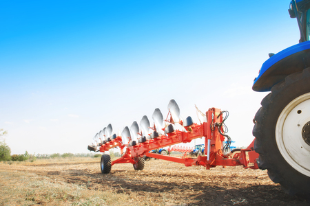 Tractor in the field with a plow. The concept of work in a fields and agriculture industry.の写真素材