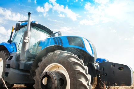 Modern tractor on a blue sky background. Concept of agricultural machinery.の写真素材